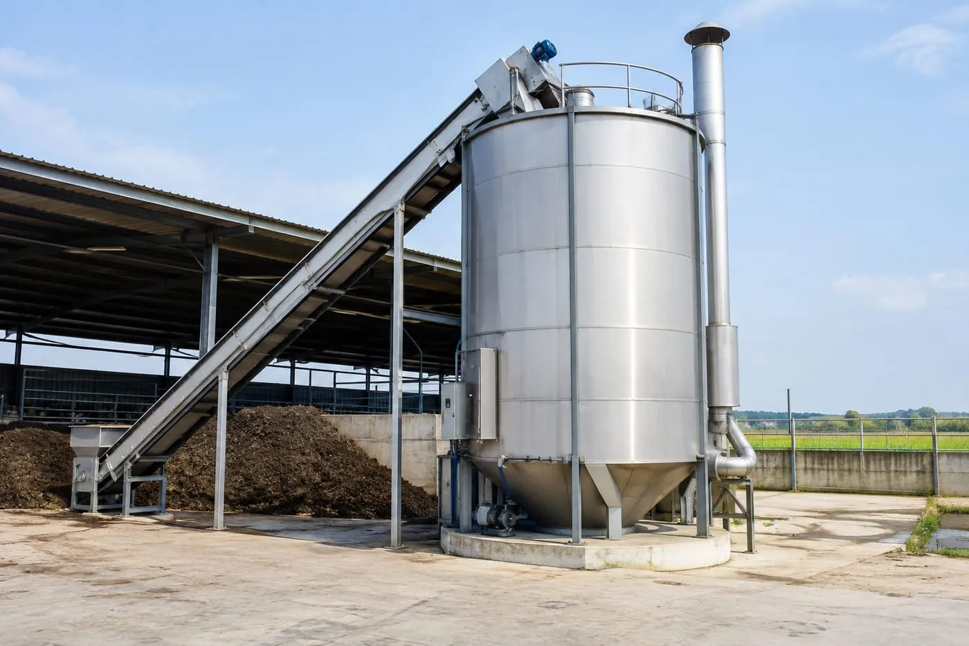 Enclosed vertical composting tank beside a shed of separated manure solids