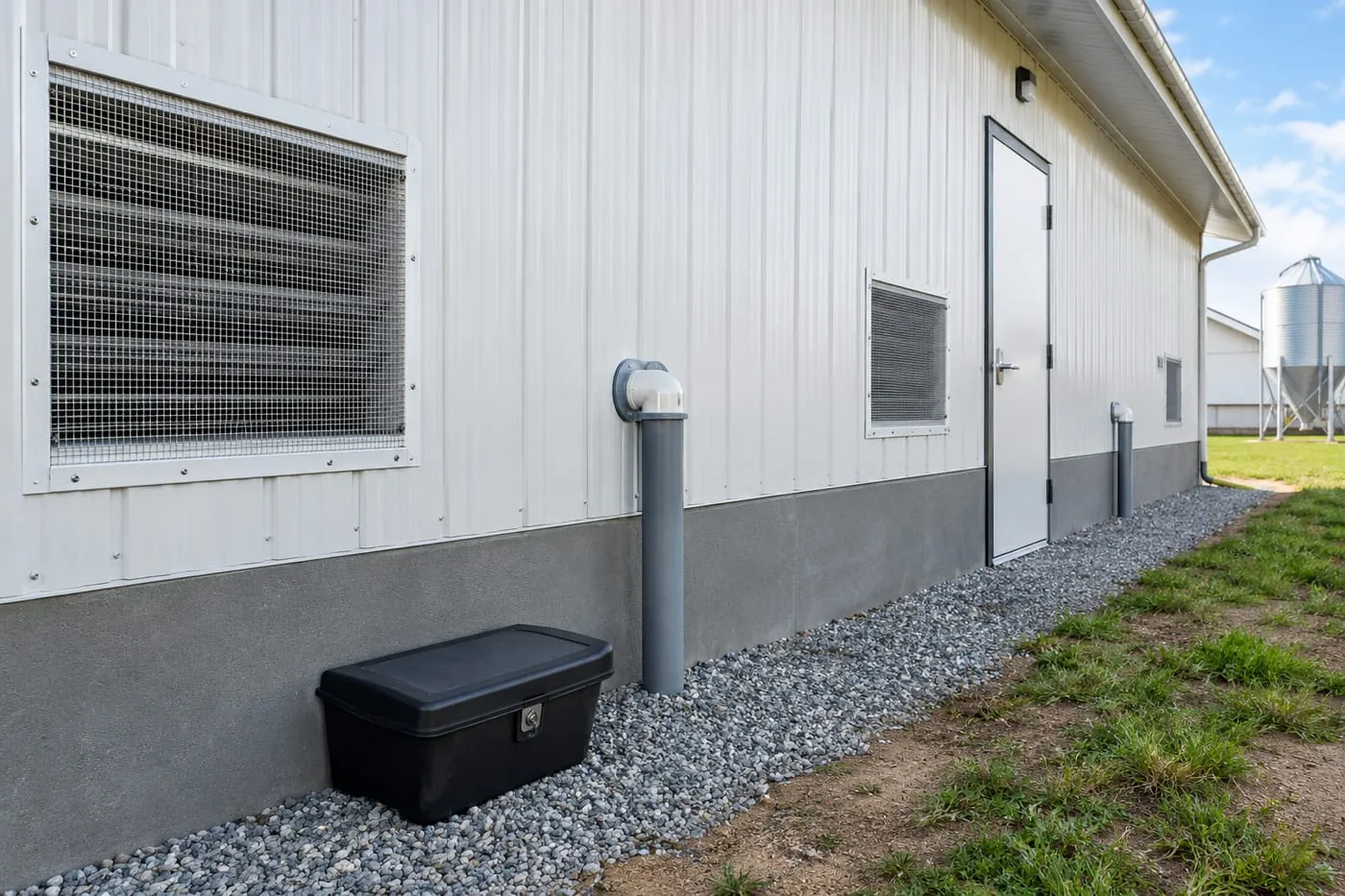 Pig house wall with mesh-covered air inlet and a rodent bait station